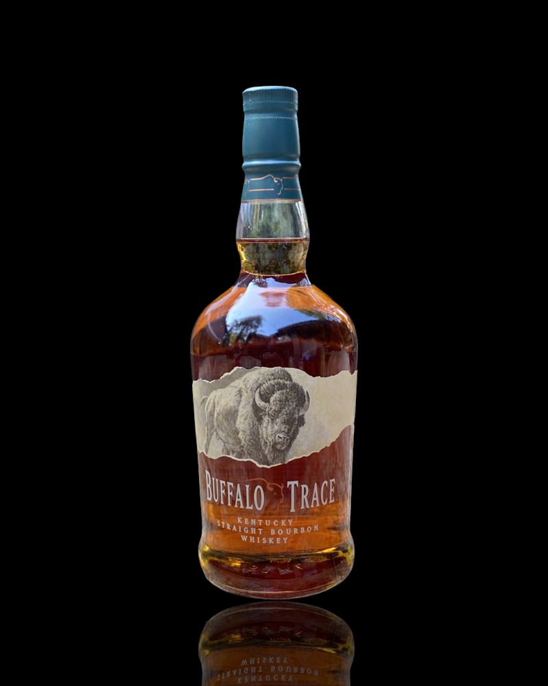 A bourbon bottle in a kraft gift bag with tissue paper on a kitchen counter