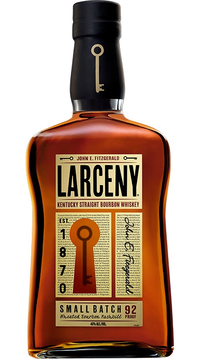 A glass of honey-colored bourbon beside honeycomb in warm light